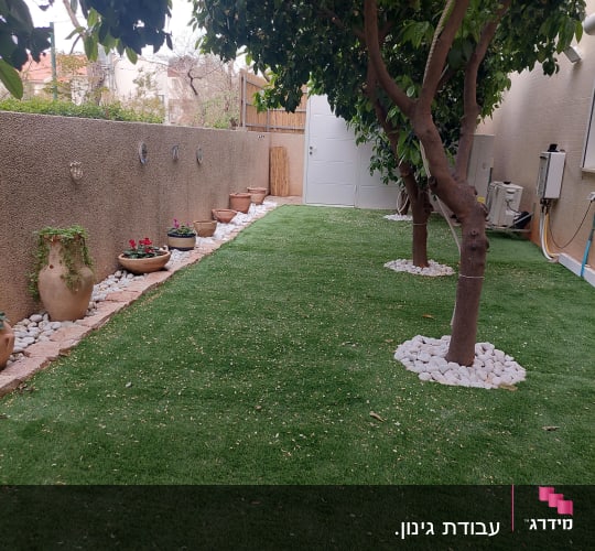 עצים ודשא עם עציצים לאורך קיר